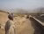 Older man with white beard wearing a faded white shirt blue turban on a dusty road