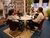 Three people seated around a round table with microphones, camera operator in studio