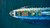 Colourful cargo boat headed out to sea - aerial view