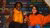 Students Emily and Rizky sit on staircase with multicolor letters with their hands in the air
