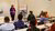 Igna Bronner, wearing a purple sweater and blue jacket, stands in front of audience during workshop