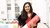 In this photo, Dr Sanchita Bakshi smiles for the camera while holding her PhD diploma