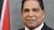 Portrait of Roodal Monilal sitting in front of the Trinidad and Tobago flag