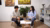 Man taking notes while chatting with woman in bright office lounge with paintings