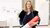 Photograph of Dr Marije Balt holding a red rolled tube in a white gallery space