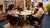 Three people with headphones sitting around a table speaking into microphones
