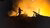 Silhouette of firefighter hosing a grain elevator after a Russian missile attack