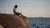 Man sitting on rock overlooking the sea