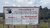 Warning sign in Thai and English, set in a grassy field.