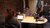 Three people wearing headphones speaking into microphones around a table in a studio