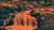 Stylized duotone orange waterfall in rocky canyon with distant city skyline