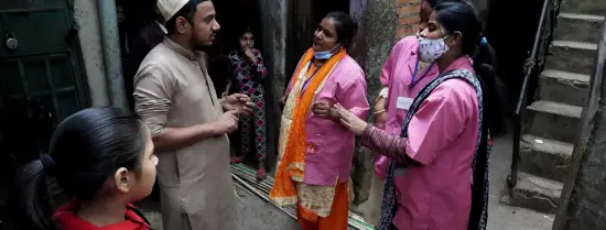 Photo of Accredited Social Health Activists (ASHAs) speaking with a man and young girl about vaccines