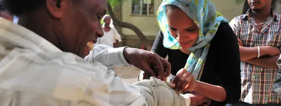A women bandages a man's arm in a health exercise with a community in Ethiopia